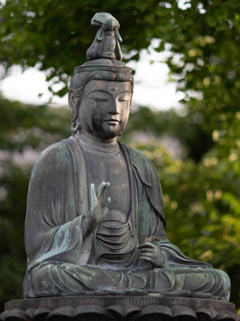 Buddha Statue mit grünen Blättern im Hintergrund